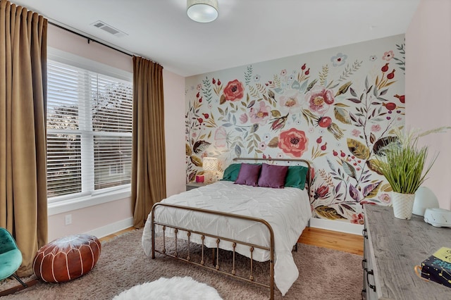 bedroom featuring visible vents, baseboards, and wood finished floors