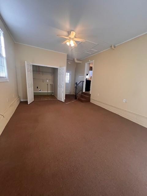 unfurnished living room featuring ceiling fan and dark carpet