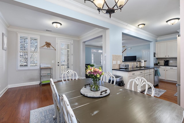 dining room featuring ornamental molding, sink, a chandelier, and dark hardwood / wood-style floors