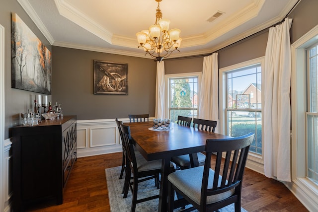 dining space with crown molding, a tray ceiling, dark hardwood / wood-style flooring, and a notable chandelier