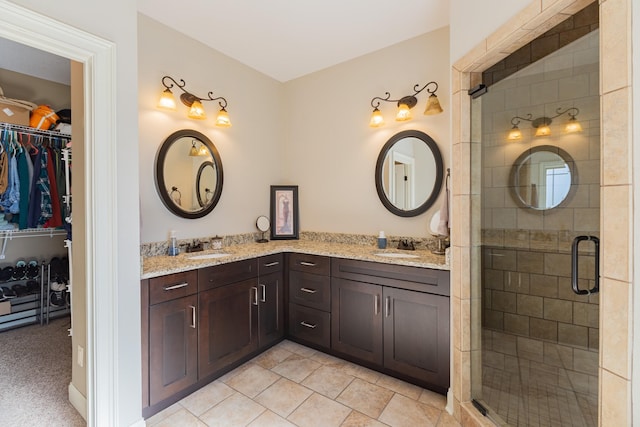 bathroom with a shower with door, vanity, and tile patterned flooring