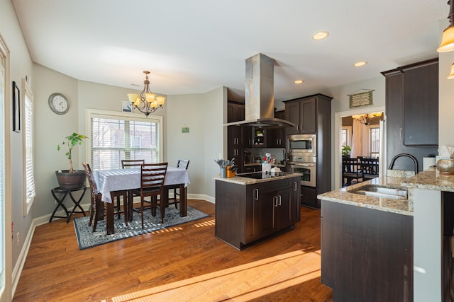 kitchen featuring sink, an inviting chandelier, hanging light fixtures, island exhaust hood, and stainless steel appliances