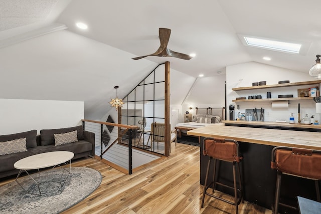 living room featuring vaulted ceiling with skylight and light wood-type flooring