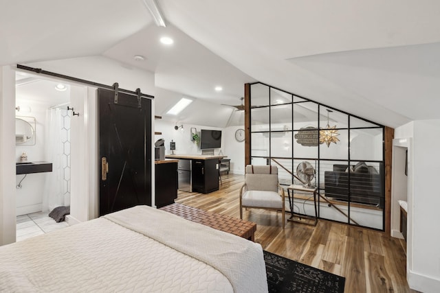 bedroom with hardwood / wood-style flooring, ensuite bath, lofted ceiling, and a barn door