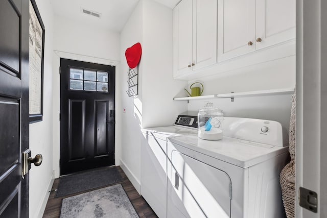 laundry area with dark hardwood / wood-style flooring, independent washer and dryer, and cabinets