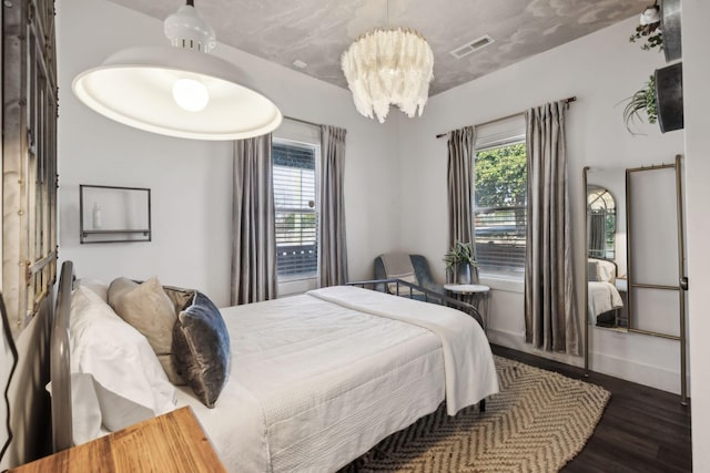 bedroom with dark hardwood / wood-style flooring, a chandelier, and multiple windows