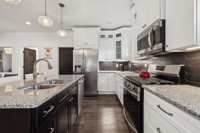 kitchen featuring stainless steel appliances, sink, decorative backsplash, and a center island with sink