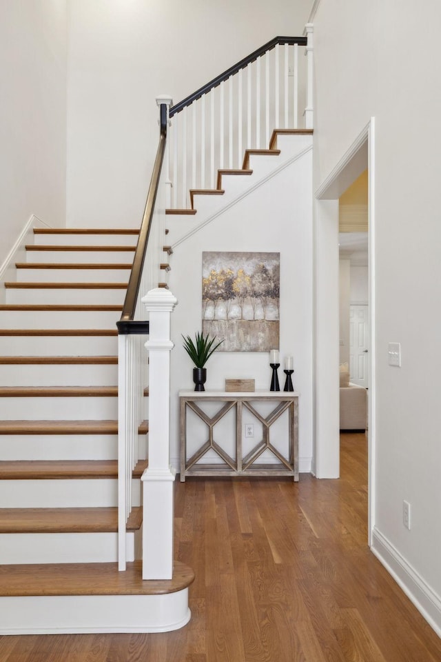 staircase with hardwood / wood-style flooring and a towering ceiling