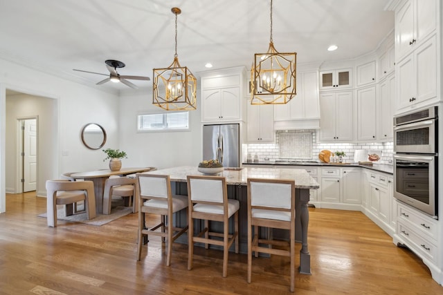 kitchen featuring white cabinetry, tasteful backsplash, a center island, hanging light fixtures, and appliances with stainless steel finishes