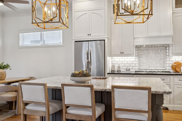 kitchen with white cabinetry, a chandelier, hanging light fixtures, ornamental molding, and appliances with stainless steel finishes