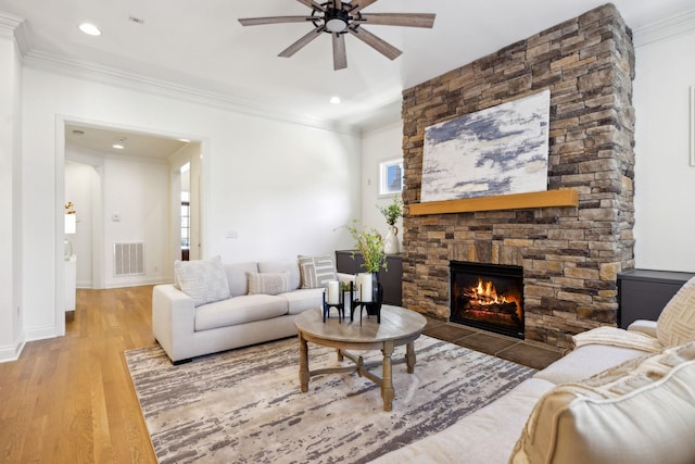 living room with hardwood / wood-style floors, a fireplace, ornamental molding, and ceiling fan