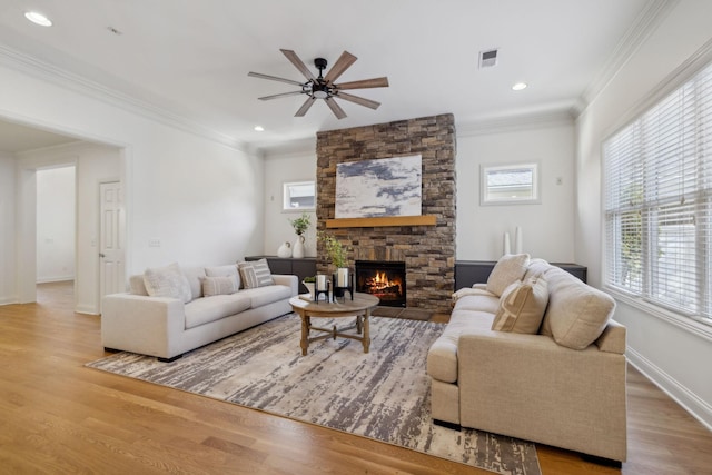 living room featuring ornamental molding, a fireplace, light hardwood / wood-style floors, and ceiling fan