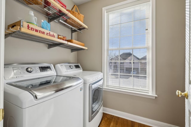 laundry room with dark hardwood / wood-style flooring, a wealth of natural light, and washing machine and clothes dryer