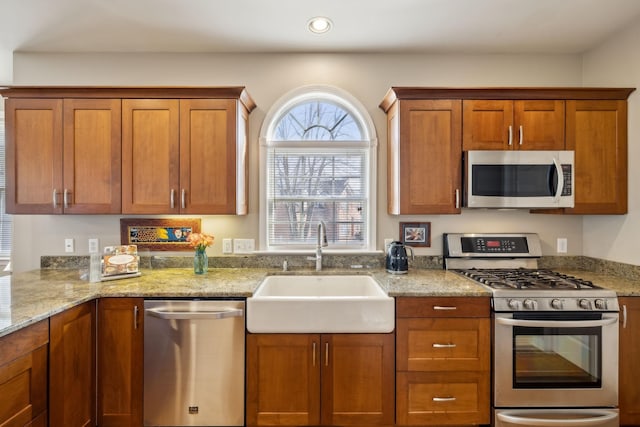 kitchen featuring light stone counters, stainless steel appliances, and sink