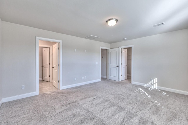 unfurnished bedroom with a spacious closet, light carpet, and a closet