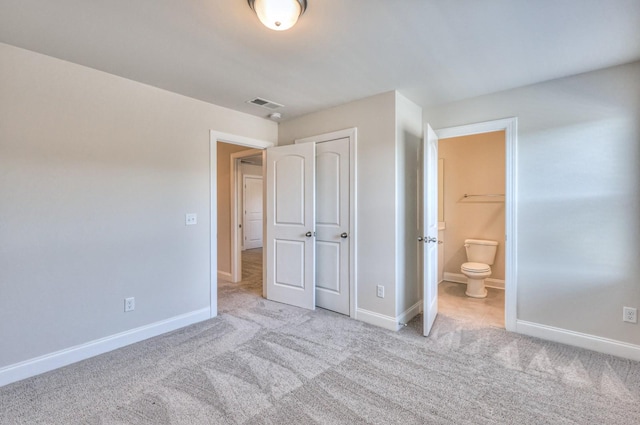 unfurnished bedroom with connected bathroom, light colored carpet, and a closet