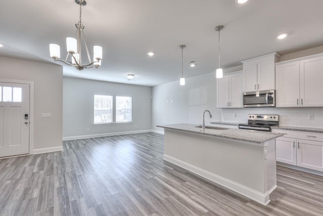 kitchen featuring white cabinetry, sink, stainless steel appliances, and hanging light fixtures