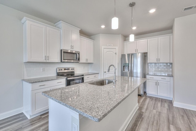 kitchen featuring stainless steel appliances, a kitchen island with sink, sink, and white cabinets