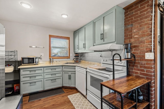 kitchen with sink, backsplash, white appliances, and light hardwood / wood-style flooring