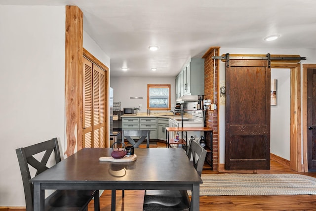 dining space with a barn door and hardwood / wood-style floors