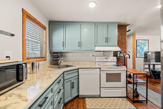 kitchen with sink, green cabinets, light hardwood / wood-style floors, light stone countertops, and white appliances