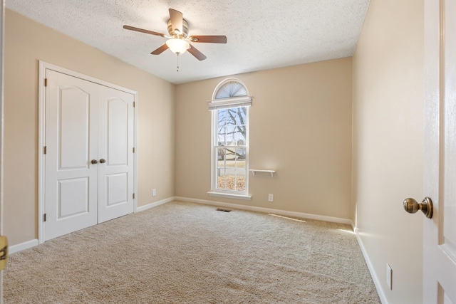 unfurnished bedroom with ceiling fan, carpet flooring, a closet, and a textured ceiling