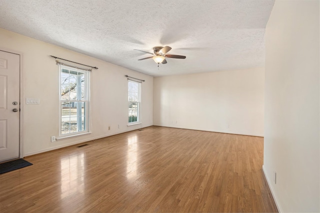 spare room featuring ceiling fan, light hardwood / wood-style floors, and a textured ceiling