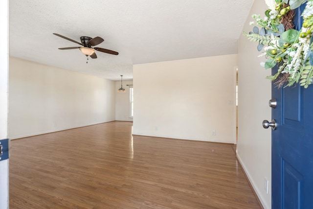 empty room featuring dark hardwood / wood-style flooring, a textured ceiling, and ceiling fan