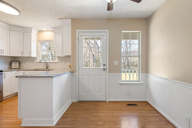 doorway to outside featuring ceiling fan, light hardwood / wood-style floors, sink, and a textured ceiling