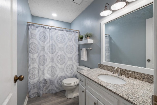 bathroom with vanity, toilet, hardwood / wood-style floors, and a textured ceiling