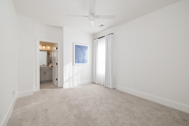 unfurnished bedroom featuring ceiling fan, ensuite bath, and light colored carpet