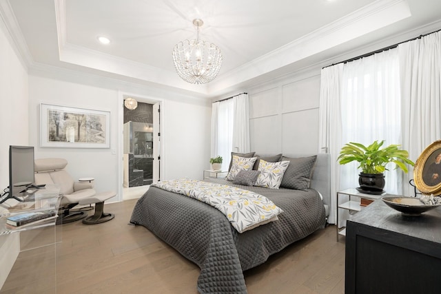 bedroom featuring ensuite bathroom, an inviting chandelier, crown molding, a raised ceiling, and hardwood / wood-style floors