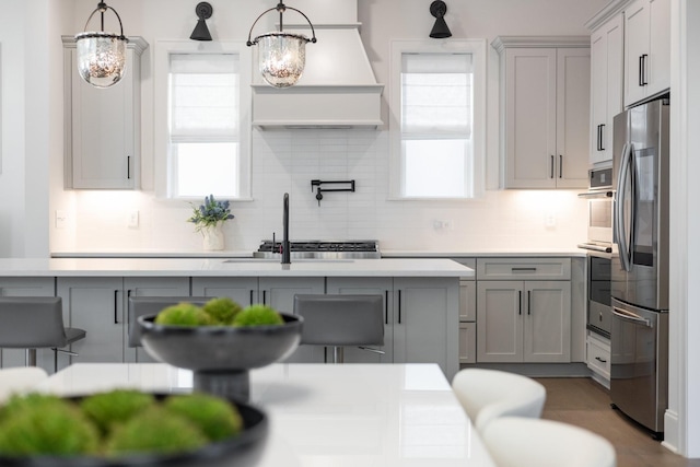 kitchen featuring appliances with stainless steel finishes, gray cabinets, and hanging light fixtures