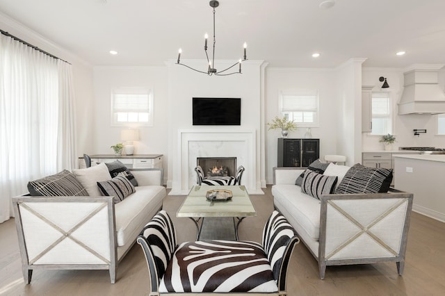 living room with a premium fireplace, crown molding, plenty of natural light, and light hardwood / wood-style floors