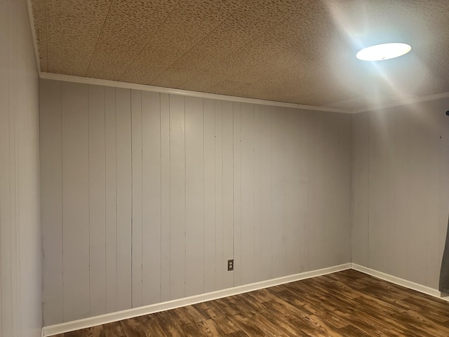 unfurnished room featuring crown molding, dark hardwood / wood-style floors, and wooden walls