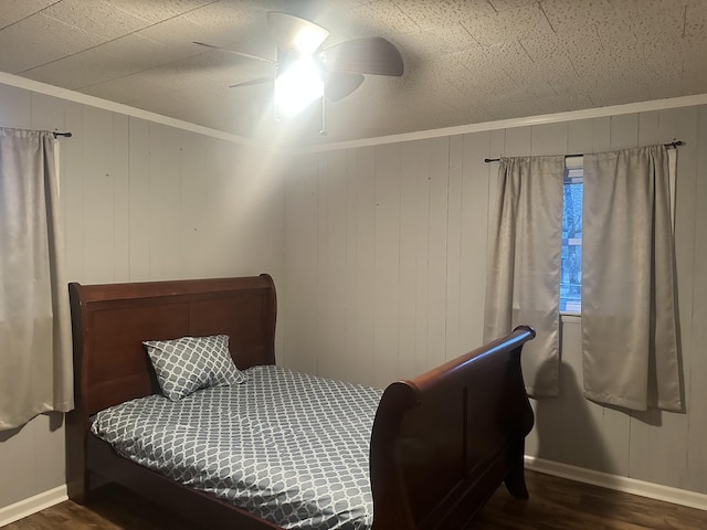 bedroom featuring dark wood-type flooring, ornamental molding, ceiling fan, and wood walls