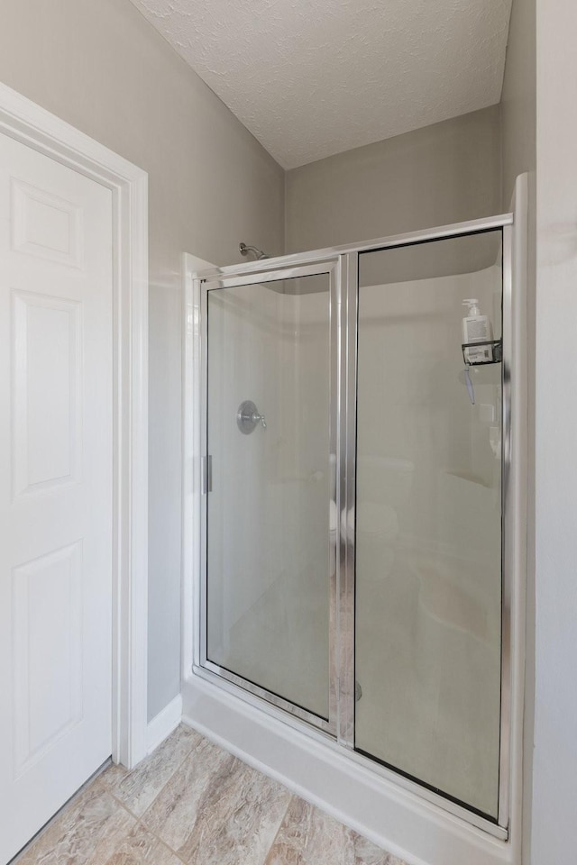 bathroom featuring a textured ceiling and a shower with shower door