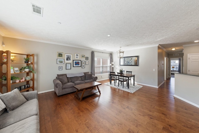 living room featuring dark wood-type flooring, ornamental molding, and a textured ceiling