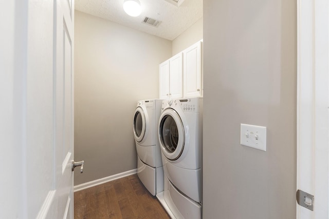 washroom with cabinets, dark hardwood / wood-style flooring, separate washer and dryer, and a textured ceiling