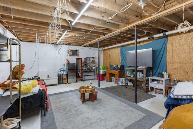 basement featuring stainless steel refrigerator and a wall mounted air conditioner