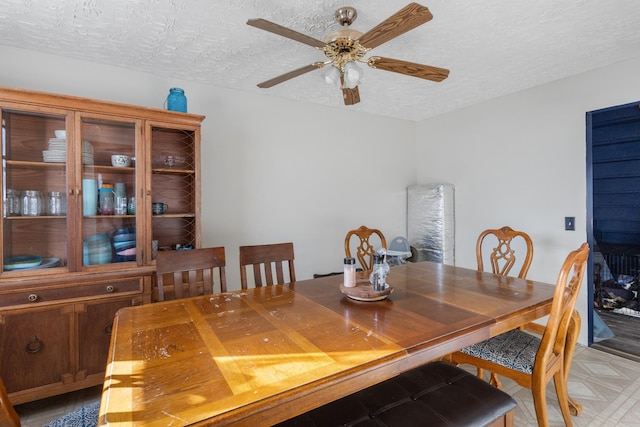 dining area with ceiling fan and a textured ceiling