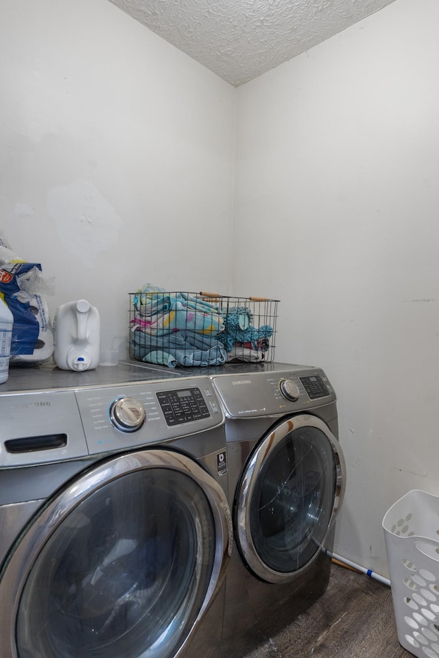 laundry room with dark wood-type flooring, washer and dryer, and a textured ceiling