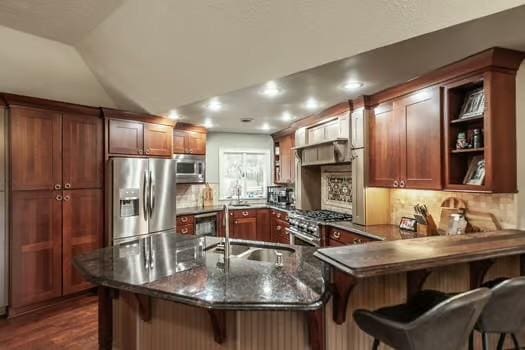 kitchen with lofted ceiling, stainless steel appliances, kitchen peninsula, and a breakfast bar