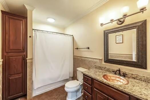 bathroom featuring toilet, tile walls, ornamental molding, vanity, and curtained shower