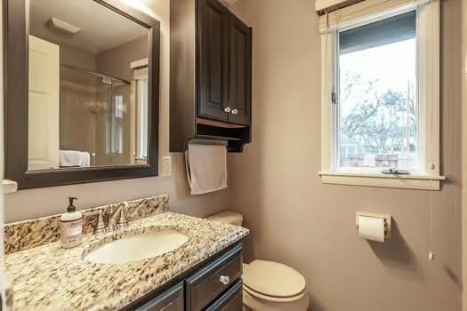 bathroom with vanity, toilet, and a shower with door