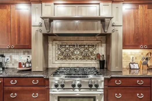 kitchen with stove, backsplash, and dark stone countertops