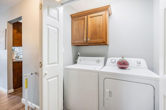 laundry area with hardwood / wood-style floors, sink, washing machine and dryer, and cabinets