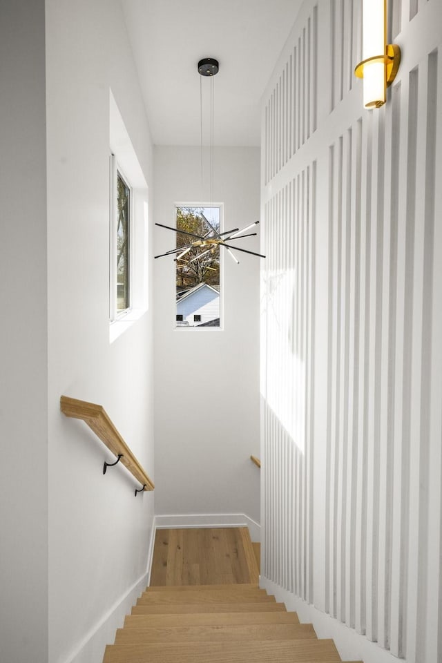 staircase with a notable chandelier and hardwood / wood-style flooring