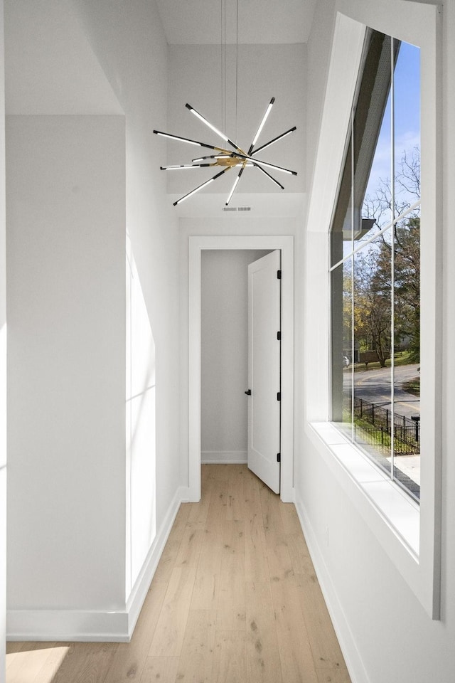 hallway featuring light hardwood / wood-style floors and a notable chandelier