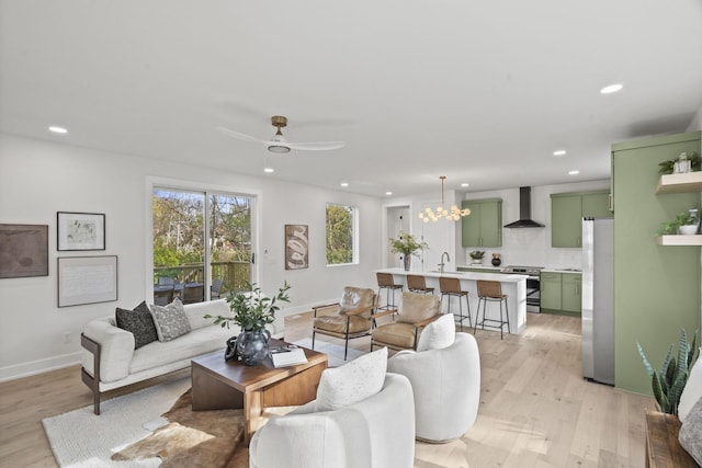 living room featuring sink, ceiling fan with notable chandelier, and light wood-type flooring